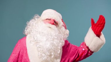 Mavi arka plan, şık beyaz sakallı Noel Baba 'ya bakıp herkesi selamlıyor. Noel Baba izole.