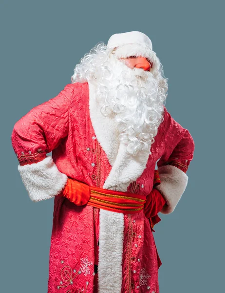 蓝色背景前视图圣诞老人红鼻子站在演播室里 右手紧握着臀部 他那浓密的胡子带着喜庆的气氛 漂亮的服装使假日很受欢迎 — 图库照片