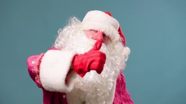Stüdyo, Noel Baba 'yı kırmızı burunlu Peder Frost' u vurdu. Kırmızı eldivenli eller, sol elinle gururlu görünüyor. Yeni yıl Noel 'i. Mavi arka plan izole edildi. Xmas, noel, yeni yıl. Tatil sunucusu
