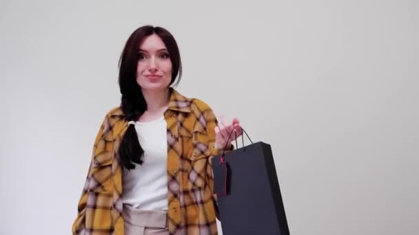 Black Friday Konzept. Glücklich lächelnde Frau zeigt auf das Preisschild mit einer Papiereinkaufstasche und genießt den Einkauf — Stockvideo