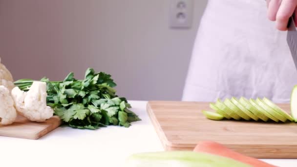 Frau Schneidet Zucchini Auf Einem Hölzernen Schneidebrett Auf Weißem Tisch — Stockvideo