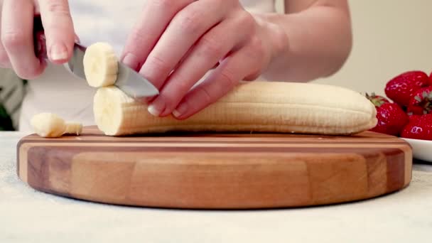 年轻女子双手整齐地在木板上切香蕉的特写镜头 — 图库视频影像
