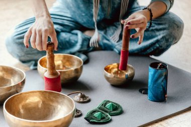 Tibet şarkı kaselerinde oynayan bir kadın yoga minderinde, ruhsal iyileşme konsepti