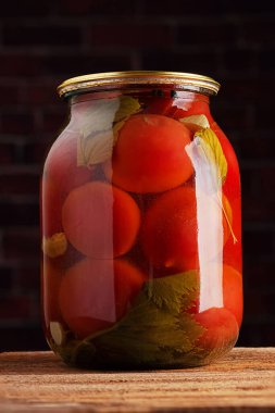 Koyu arkaplanda ev yapımı konserve domates kavanozu.