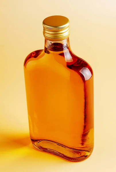 A small flat glass brandy bottle on a uniform background