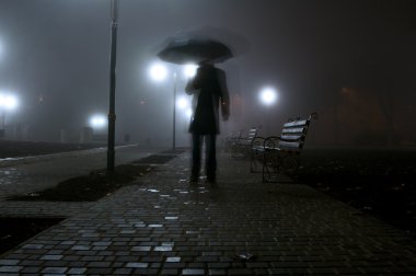 Man with umbrella in the night park