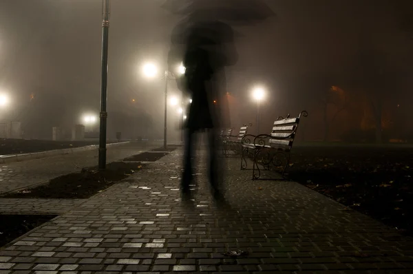 Man med paraply i parken natt — Stockfoto