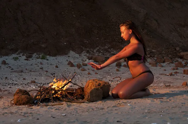 Beautiful woman near the fire on the beach — Stock Photo, Image