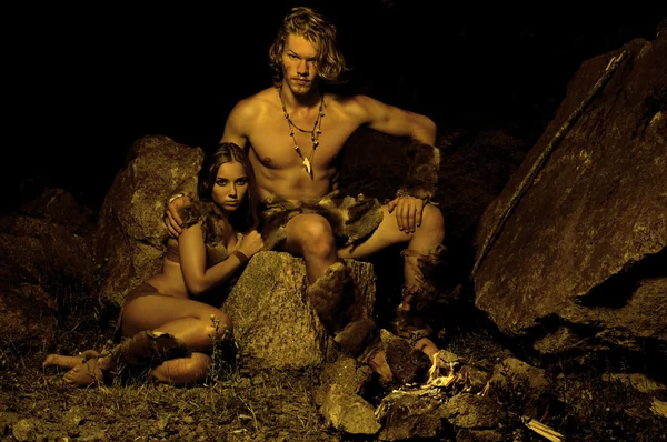 L'uomo primitivo e la sua donna seduti vicino al fuoco nella grotta Foto Stock