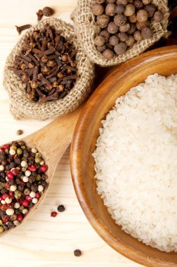 kaşık ve torbalar içinde ahşap masa arka plan üzerinde ahşap kase pilav baharat