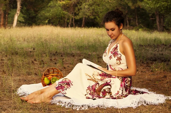 Μελαχρινή όμορφη γυναίκα που διαβάζει το βιβλίο σε ένα λιβάδι — Φωτογραφία Αρχείου