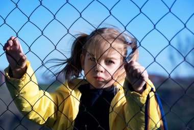 Sınırda kafes yakınında sarı ve mavi kurdeleli güzel bir Ukraynalı kızın portresi. Ukrayna 'yı kurtarmak için yardım istiyor. Savaşı durdurun..