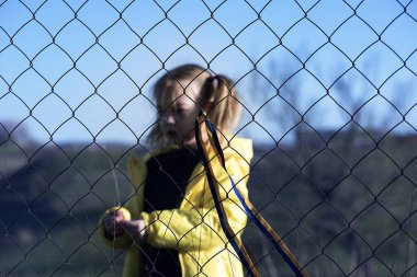 Sınırda kafes yakınında sarı ve mavi kurdeleli güzel bir Ukraynalı kızın portresi. Ukrayna 'yı kurtarmak için yardım istiyor. Savaşı durdurun..