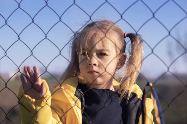 Sınırda kafes yakınında sarı ve mavi kurdeleli güzel bir Ukraynalı kızın portresi. Ukrayna 'yı kurtarmak için yardım istiyor. Savaşı durdurun..