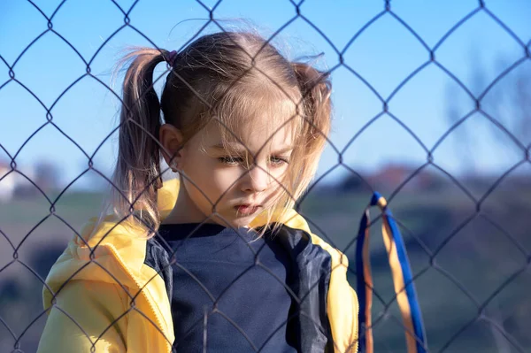 Sınırda kafes yakınında sarı ve mavi kurdeleli güzel bir Ukraynalı kızın portresi. Ukrayna 'yı kurtarmak için yardım istiyor. Savaşı durdurun..