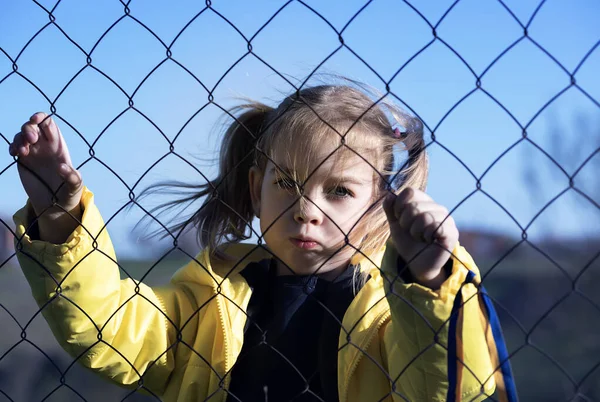Sınırda kafes yakınında sarı ve mavi kurdeleli güzel bir Ukraynalı kızın portresi. Ukrayna 'yı kurtarmak için yardım istiyor. Savaşı durdurun..