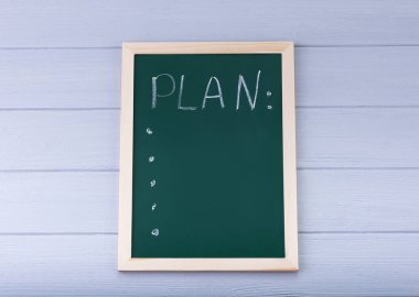 Yeşil bir karatahtaya beyaz tebeşirle yazılmış el yazısı.