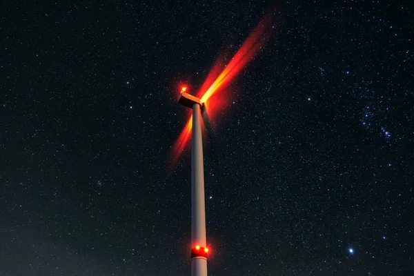 Night photo of a windmill and stars with abstract lighting. Wind turbine at night against the background of stars. Environment and Renewable Energy