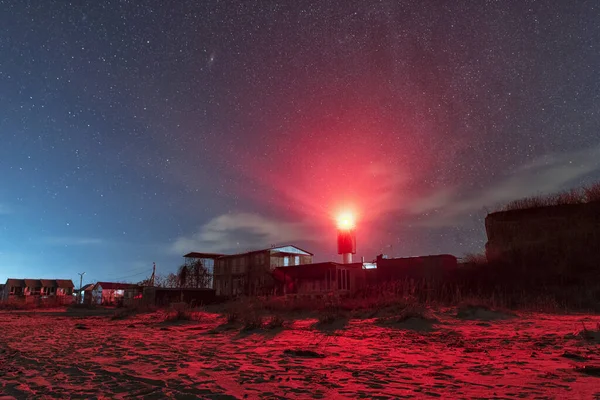 Beautiful night sky behind a shining lighthouse. Starry night and Milky Way. Abstract lighting