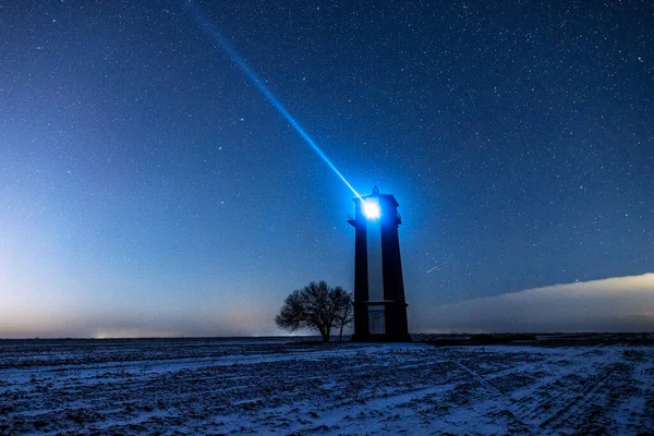 Bright lighthouse beaconing at the end of the milky way. Beautiful lighthouse. Night in the field.