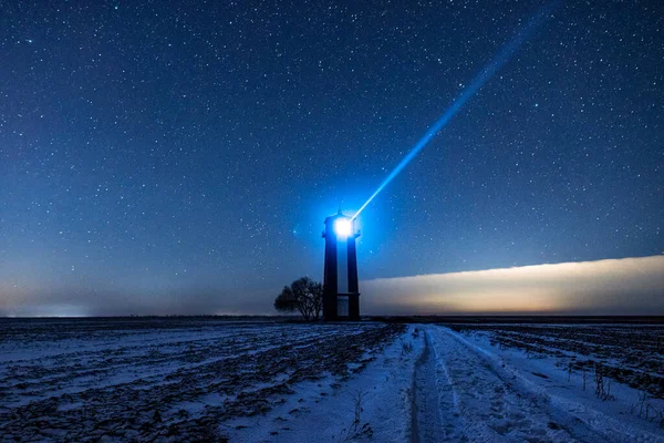 Bright lighthouse beaconing at the end of the milky way. Beautiful lighthouse. Night in the field.