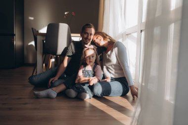 Genç ebeveynler ve kızlar oynuyor, eğleniyor, sonbaharda sıcacık bir evde sarılıyorlar. 