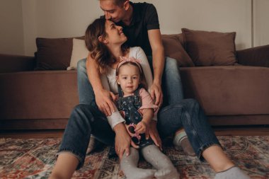 Genç ebeveynler ve kızlar oynuyor, eğleniyor, sonbaharda sıcacık bir evde sarılıyorlar. 