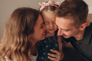 Genç ebeveynler ve kızlar oynuyor, eğleniyor, sonbaharda sıcacık bir evde sarılıyorlar. 