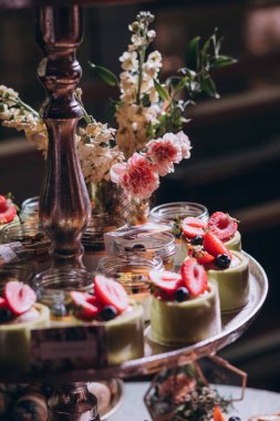 Lokantada şekerli büfe masası. Çiçeklerle süslenmiş bir yüzeyde kekler, pastalar, gurme şekerlemeler. 