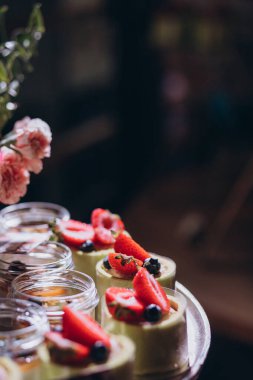Lokantada şekerli büfe masası. Çiçeklerle süslenmiş bir yüzeyde kekler, pastalar, gurme şekerlemeler. 
