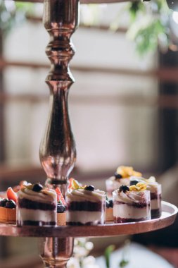 Lokantada şekerli büfe masası. Çiçeklerle süslenmiş bir yüzeyde kekler, pastalar, gurme şekerlemeler. 