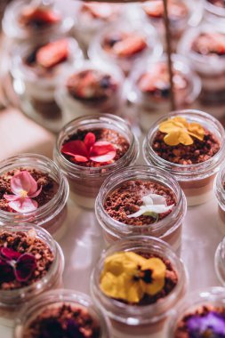 Lokantada şekerli büfe masası. Çiçeklerle süslenmiş bir yüzeyde kekler, pastalar, gurme şekerlemeler. 