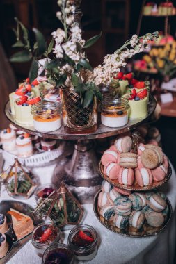 Lokantada şekerli büfe masası. Çiçeklerle süslenmiş bir yüzeyde kekler, pastalar, gurme şekerlemeler. 