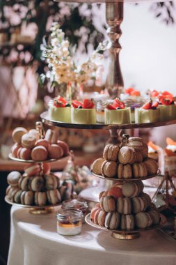 Lokantada şekerli büfe masası. Çiçeklerle süslenmiş bir yüzeyde kekler, pastalar, gurme şekerlemeler. 
