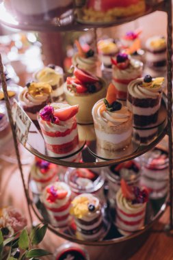 Lokantada şekerli büfe masası. Çiçeklerle süslenmiş bir yüzeyde kekler, pastalar, gurme şekerlemeler. 