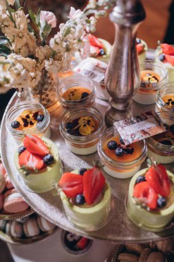 Lokantada şekerli büfe masası. Çiçeklerle süslenmiş bir yüzeyde kekler, pastalar, gurme şekerlemeler. 