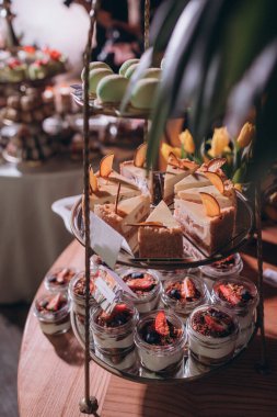 Lokantada şekerli büfe masası. Çiçeklerle süslenmiş bir yüzeyde kekler, pastalar, gurme şekerlemeler. 