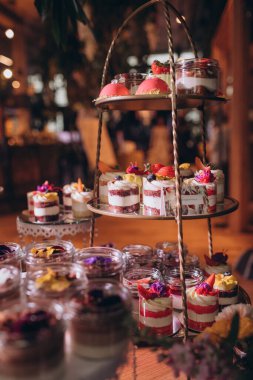 Lokantada şekerli büfe masası. Çiçeklerle süslenmiş bir yüzeyde kekler, pastalar, gurme şekerlemeler. 