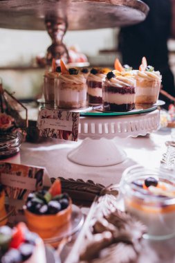 Lokantada şekerli büfe masası. Çiçeklerle süslenmiş bir yüzeyde kekler, pastalar, gurme şekerlemeler. 