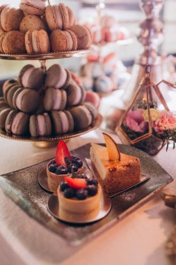 Lokantada şekerli büfe masası. Çiçeklerle süslenmiş bir yüzeyde kekler, pastalar, gurme şekerlemeler. 