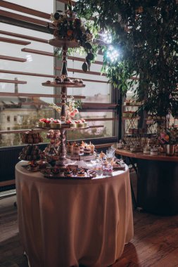 Lokantada şekerli büfe masası. Çiçeklerle süslenmiş bir yüzeyde kekler, pastalar, gurme şekerlemeler. 