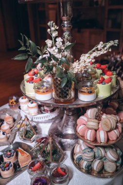 Lokantada şekerli büfe masası. Çiçeklerle süslenmiş bir yüzeyde kekler, pastalar, gurme şekerlemeler. 