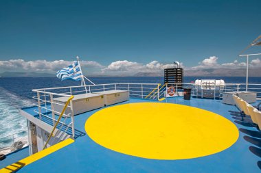 Mavi gemide helikopterler için sarı helikopter pisti işareti olan parlak kontrast sahnesinde güneş ışığıyla aydınlatılan Yunanistan bayrağı