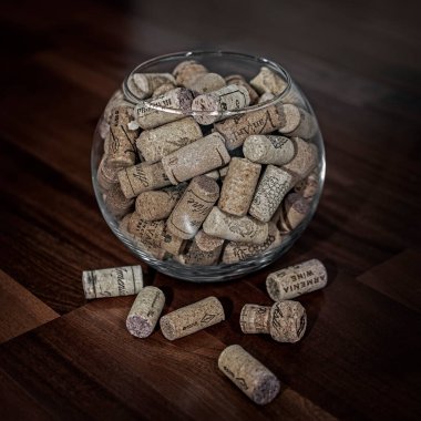 Erivan, Ermenistan - 02 Şubat 2022: Kırmızı, beyaz ve köpüklü şarap mantarları yuvarlak cam vazoda bulanık ahşap zemin zeminine karşı