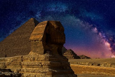 Geceleyin Samanyolu Galaksisi 'nin altında firavunların mezarlarını koruyan arka planda Khafre Piramidi olan Büyük Giza Sfenksi. Kahire, Mısır