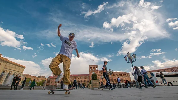 埃里温 亚美尼亚 2022年4月9日 动态低广角镜头 年轻男子在共和国广场上滑板 在戏剧性的乌云蓝天下 — 图库照片