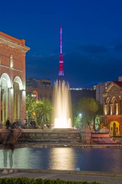 Erivan, Ermenistan - 09 Nisan 2022: Cumhuriyet Meydanı 'nda arka planda ışıklandırılmış TV kulesi ile şarkı ve dans çeşmeleri