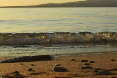 Yaklaşan bir dalgayla kumlu, terk edilmiş deniz kıyısı.