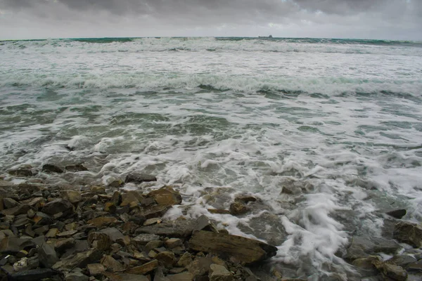 秋风汹涌的大海 海浪汹涌在海滨的岩石沙滩上 水上飞机在冲浪后离开大海 一艘船在地平线上 云彩笼罩大海 — 图库照片
