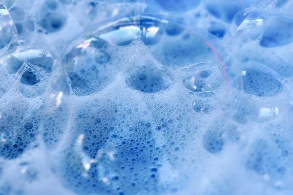 Bubble texture in blue foam, macro photography, theme of cleanliness and hygiene.